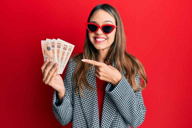 a young brunette woman holds a wad of UK &pound;10 bank notes