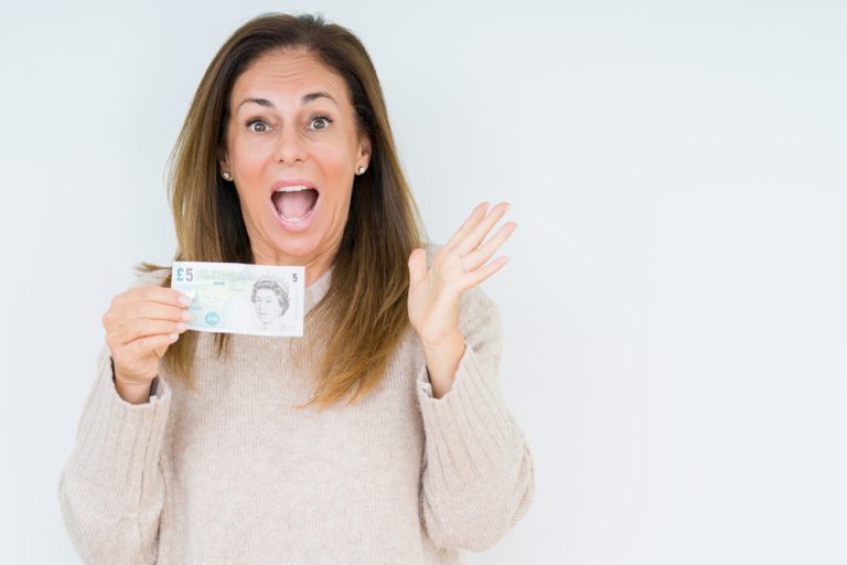 Middle age woman holding 5 pounds bank note over isolated background very happy and excited to get free &pound;5 with zilch referral offer