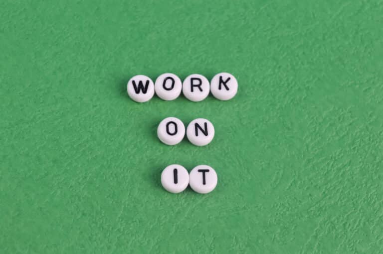 White beads with black letters on a green background spell out "WORK ON IT" in three rows, echoing the ethos of popular side hustle quotes.